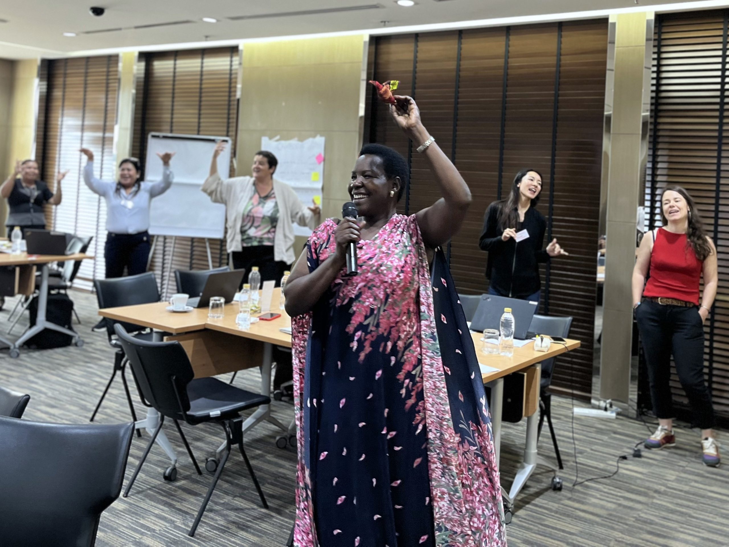 Sylvia Achan (SEMA member) raising her hand showing a stuffed bird created by SEMA members